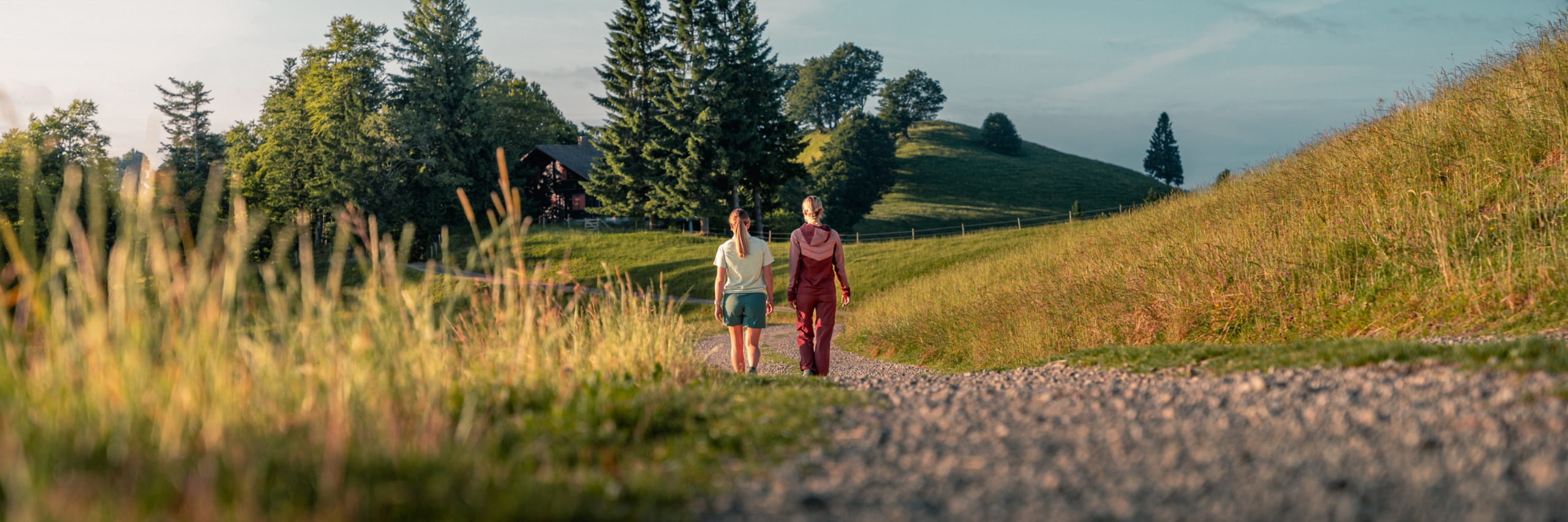 Zwei Frauen in Sherpa-Bekleidung wandern auf einem Bergweg durch die Natur.